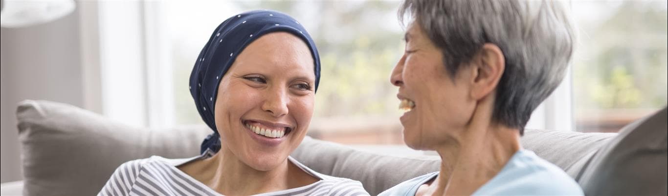 Woman with scarf around her head laughs with older woman