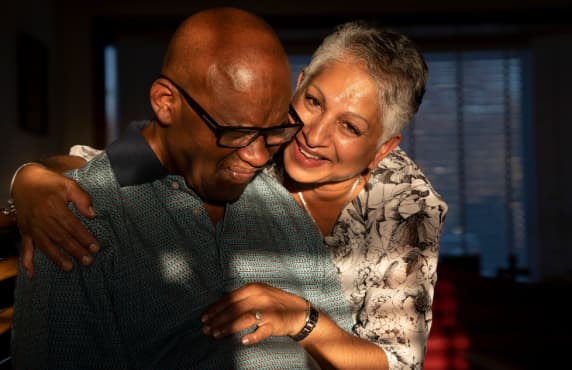 Woman with her arm around a man in glasses