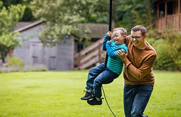 Man and child playing on a rope swing