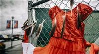 A red dress hanging outside on a chain link fence, a symbol of Canada’s National Crisis of Missing, Murdered and Exploited Indigenous People