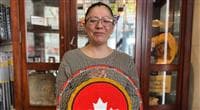 Janice Johnstone, an artist from the Muskeg Lake Cree Nation, holding a Petro-Canada logo made with traditional Indigenous beadwork techniques