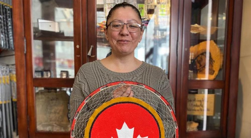 Janice Johnstone, an artist from the Muskeg Lake Cree Nation, holding a Petro-Canada logo made with traditional Indigenous beadwork techniques