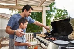 Father and son grilling over an outdoor barbeque