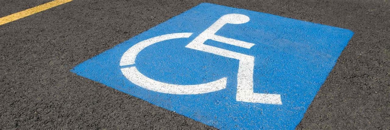 Icône de fauteuil roulant bleue dans un stationnement.