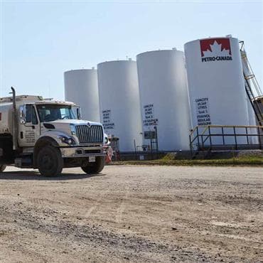 Un camion Petro-Canada à côté de gros réservoirs de carburant.