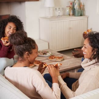 A family sitting in their cozy living room, eating pizza.