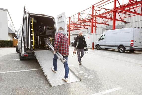 Two men keeping film production equipment in a van